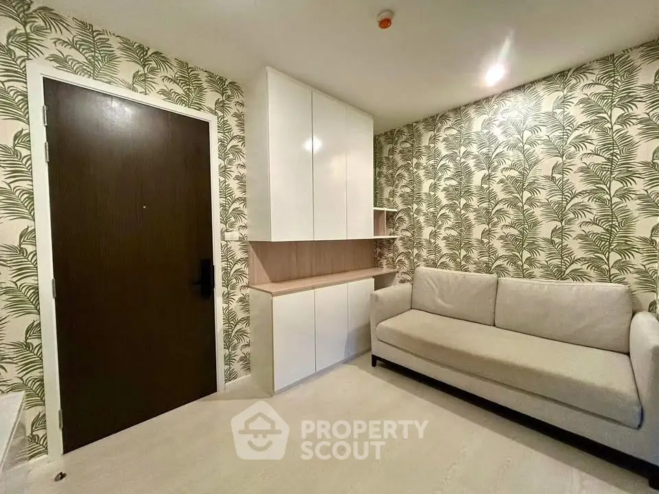 Stylish living room with modern sofa and tropical wallpaper, featuring sleek storage cabinets.