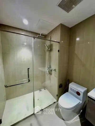 Modern bathroom with glass shower enclosure and sleek fixtures in a contemporary apartment.