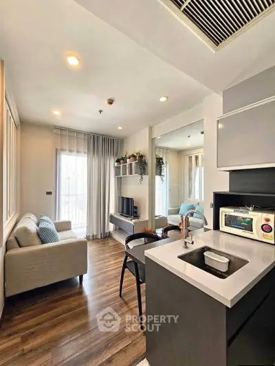 Modern living room with open kitchen, stylish decor, and natural light