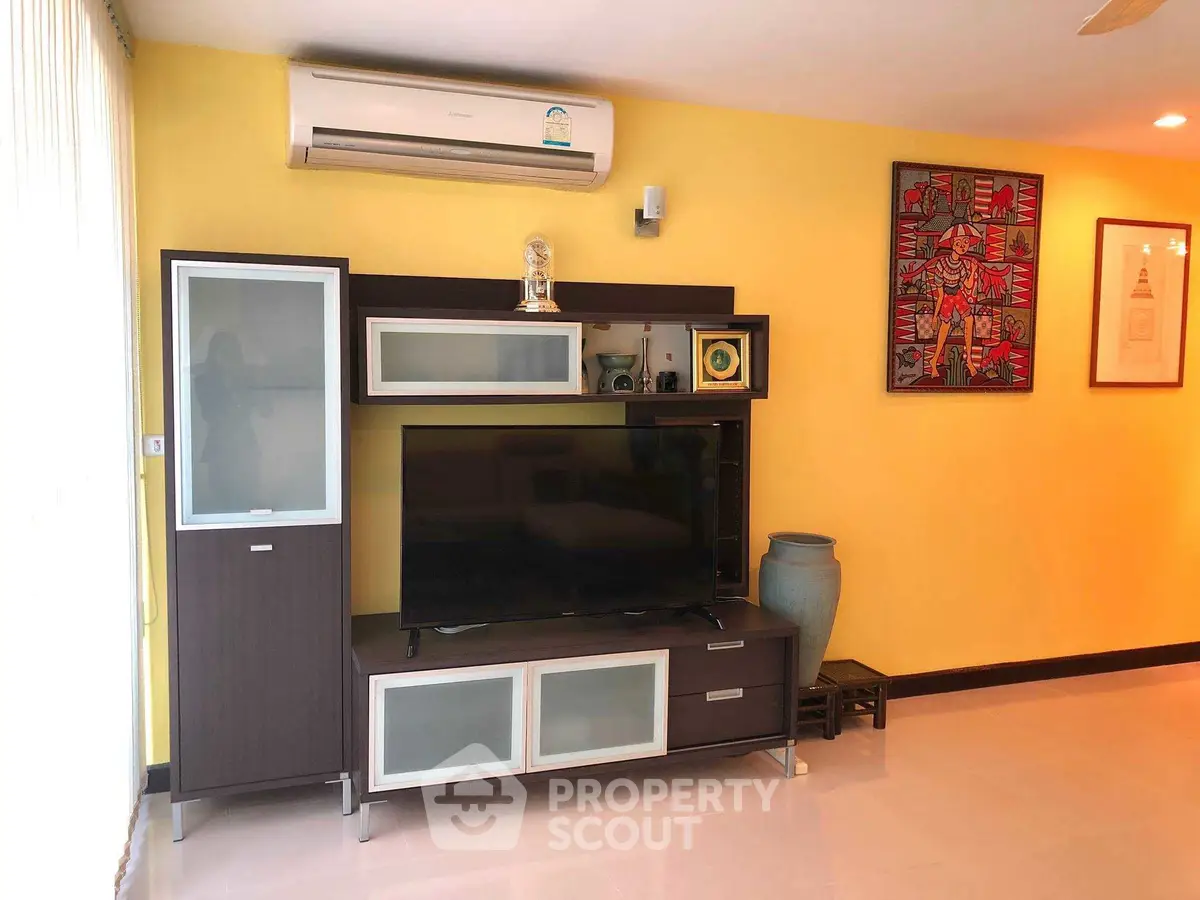 Stylish living room with modern entertainment center and vibrant yellow accent wall.