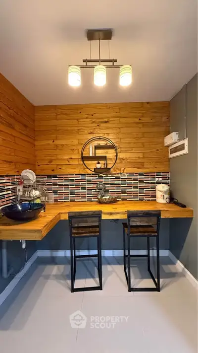 Charming kitchen with wooden accents and modern lighting, featuring a cozy breakfast bar and stylish backsplash.