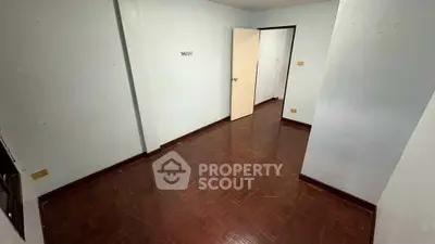 Spacious empty room with wooden flooring and white walls, ideal for customization.