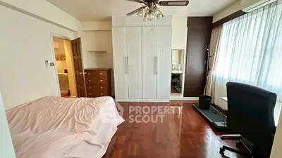 Spacious bedroom with wooden flooring, large wardrobe, and natural light