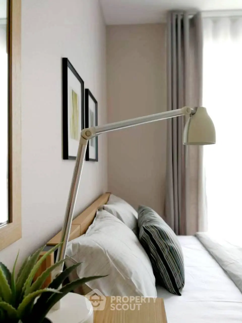 Cozy bedroom with modern decor and natural light, featuring stylish lamp and framed art.