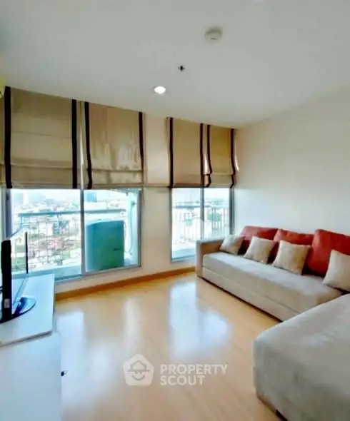 Bright living room with large windows and cozy sofa, offering a stunning city view.