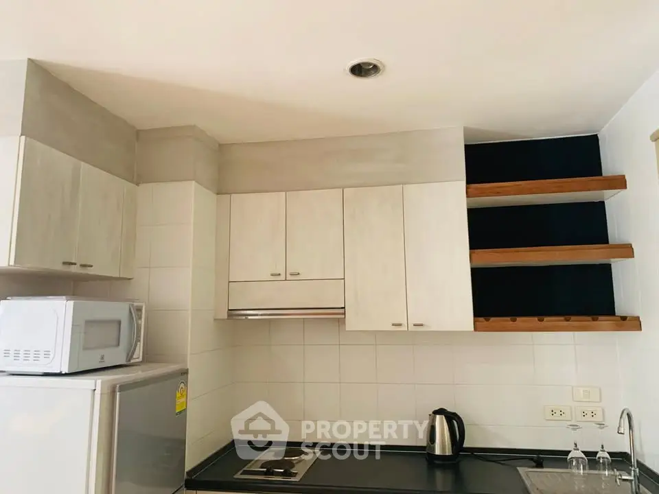 Modern kitchen with sleek cabinets, stainless steel appliances, and open shelving.