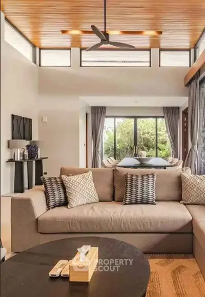 Luxurious living room with modern decor and large windows overlooking a lush garden.