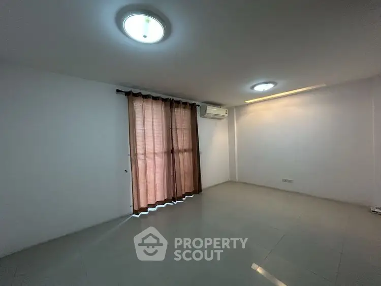 Spacious empty room with tiled floor and large window, ideal for customization.