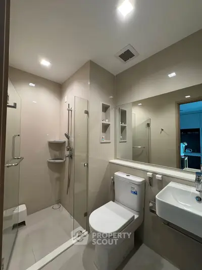 Modern bathroom with glass shower and sleek fixtures in contemporary apartment.