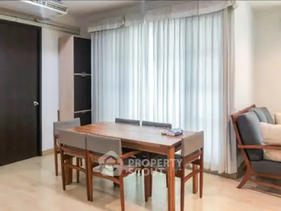 Cozy dining area with wooden table and chairs, adjacent to a comfortable seating space.