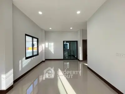 Spacious modern living room with large windows and glossy floors in a contemporary home.