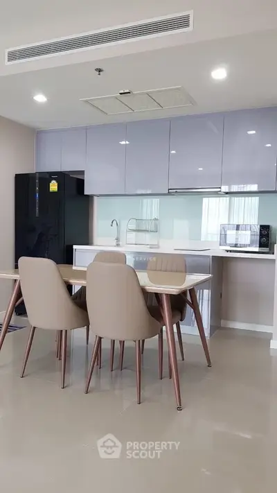 Modern kitchen with sleek cabinetry and dining area in contemporary apartment