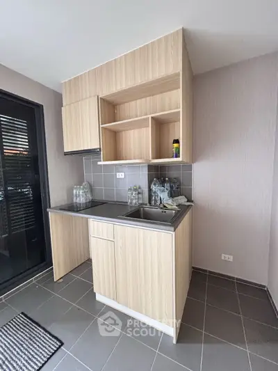 Modern compact kitchen with sleek cabinetry and stainless steel sink in a stylish apartment.