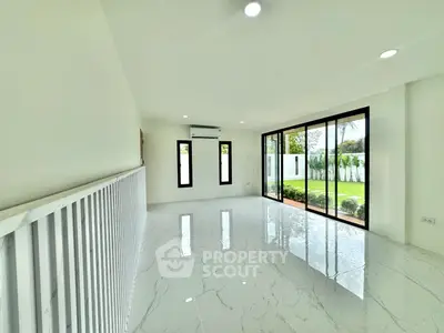 Spacious modern living room with large windows and garden view, featuring sleek white interiors and glossy flooring.
