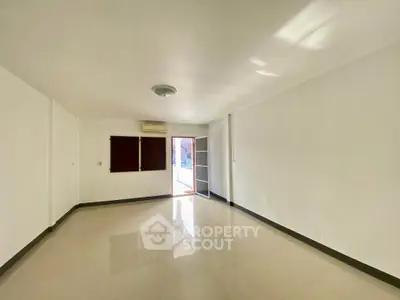Spacious empty room with glossy tiled floor and natural light