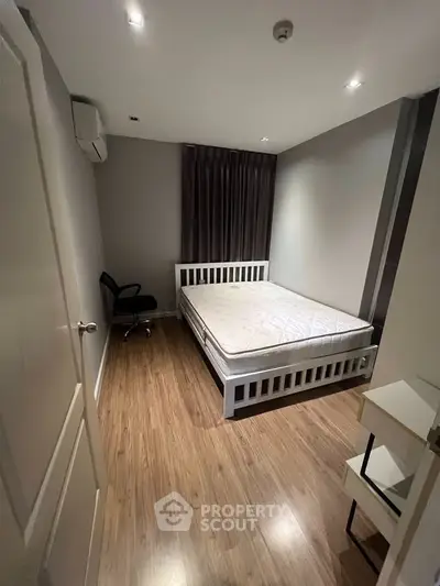 Cozy bedroom with wooden flooring and modern furnishings in a stylish apartment.