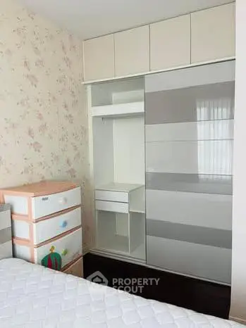 Charming bedroom with built-in wardrobe and floral wallpaper, perfect for cozy living.