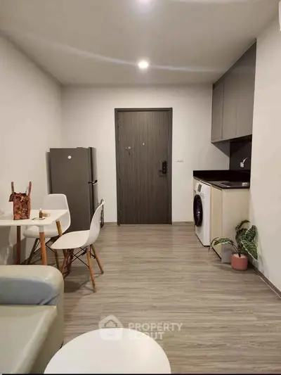Modern compact living room with kitchen and washing machine, featuring sleek design and cozy ambiance.