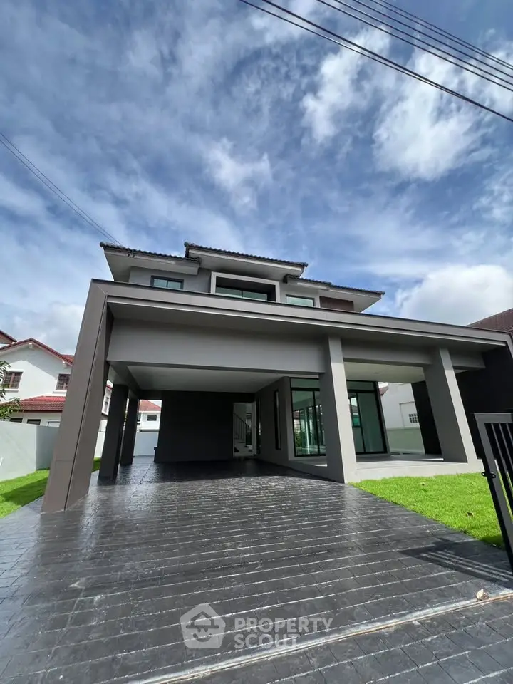 Modern two-story house with spacious driveway and sleek architectural design under a clear blue sky.