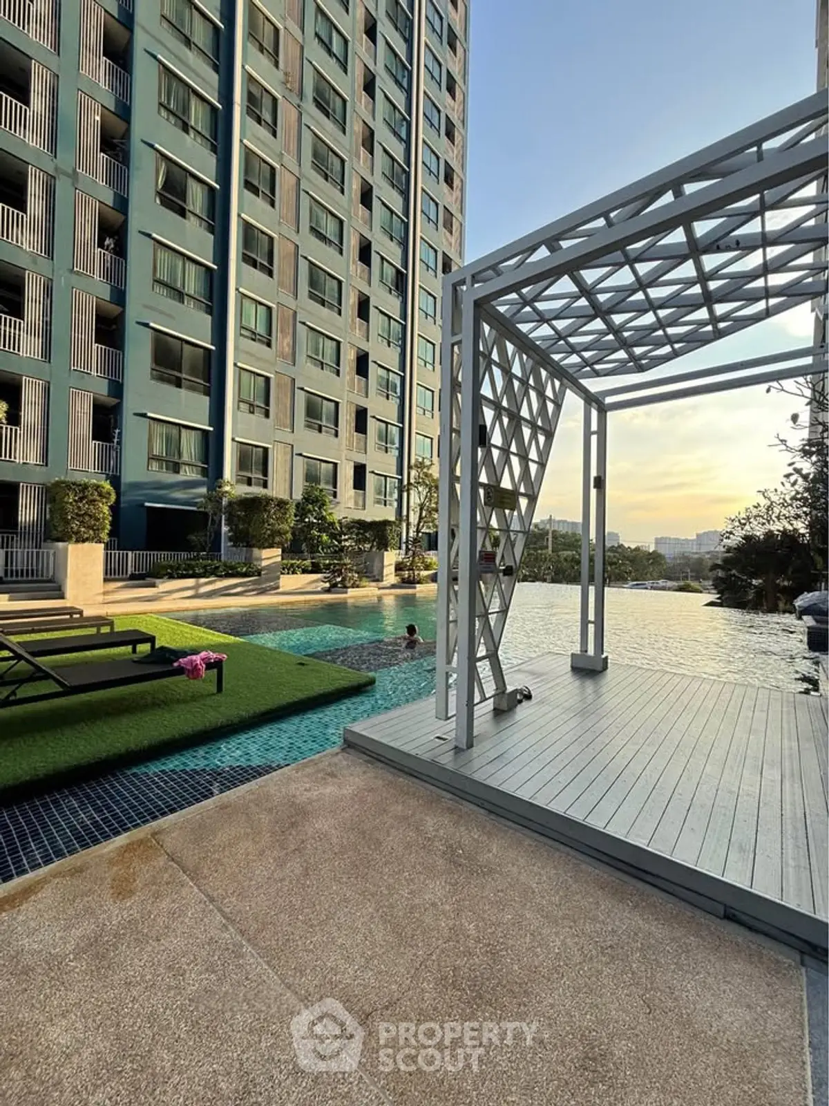 Modern apartment building with luxurious pool and stylish outdoor area at sunset.