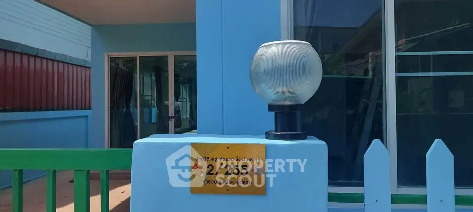 Charming blue exterior of a modern home with glass door and decorative lamp.