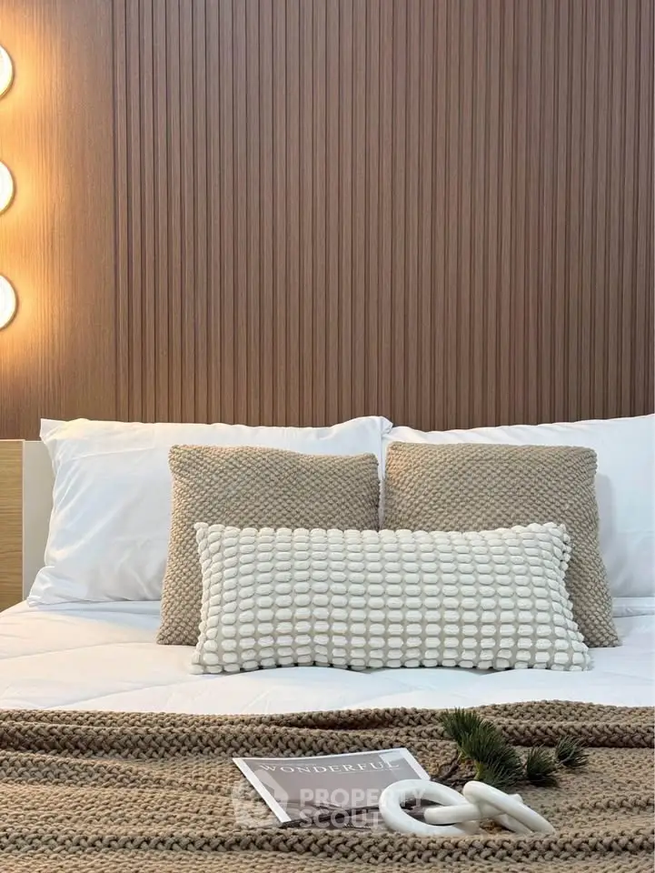 Cozy bedroom with textured pillows and modern lighting, perfect for relaxation.
