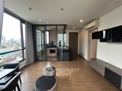 Modern living room with city view, featuring sleek wooden flooring and stylish furniture.