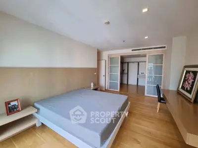 Spacious bedroom with modern design and wooden flooring, featuring a large bed and stylish decor.