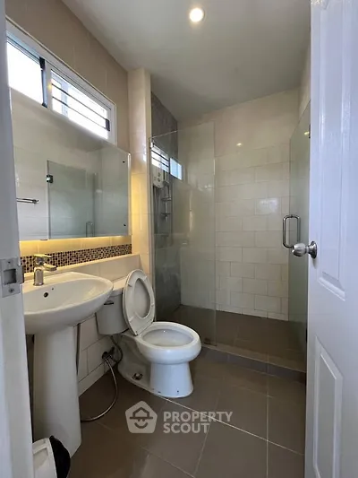 Modern bathroom with glass shower, white fixtures, and tiled walls in a contemporary home.