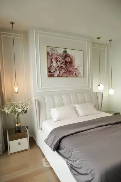 Luxurious bedroom with elegant decor and plush bedding, featuring modern pendant lights and floral artwork.