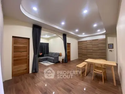 Spacious modern living room with wooden flooring and elegant ceiling lights.