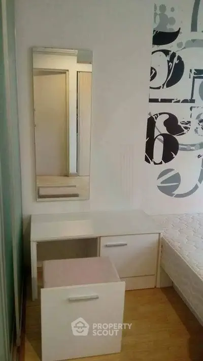 Modern bedroom with stylish vanity and mirror, featuring sleek white furniture and contemporary wall art.