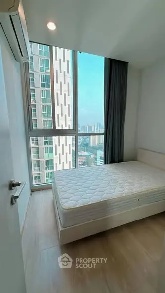 Modern bedroom with large window offering stunning city view in high-rise apartment.