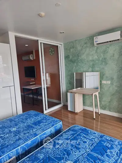 Modern bedroom with twin beds, air conditioning, and a stylish vanity set in a vibrant apartment.