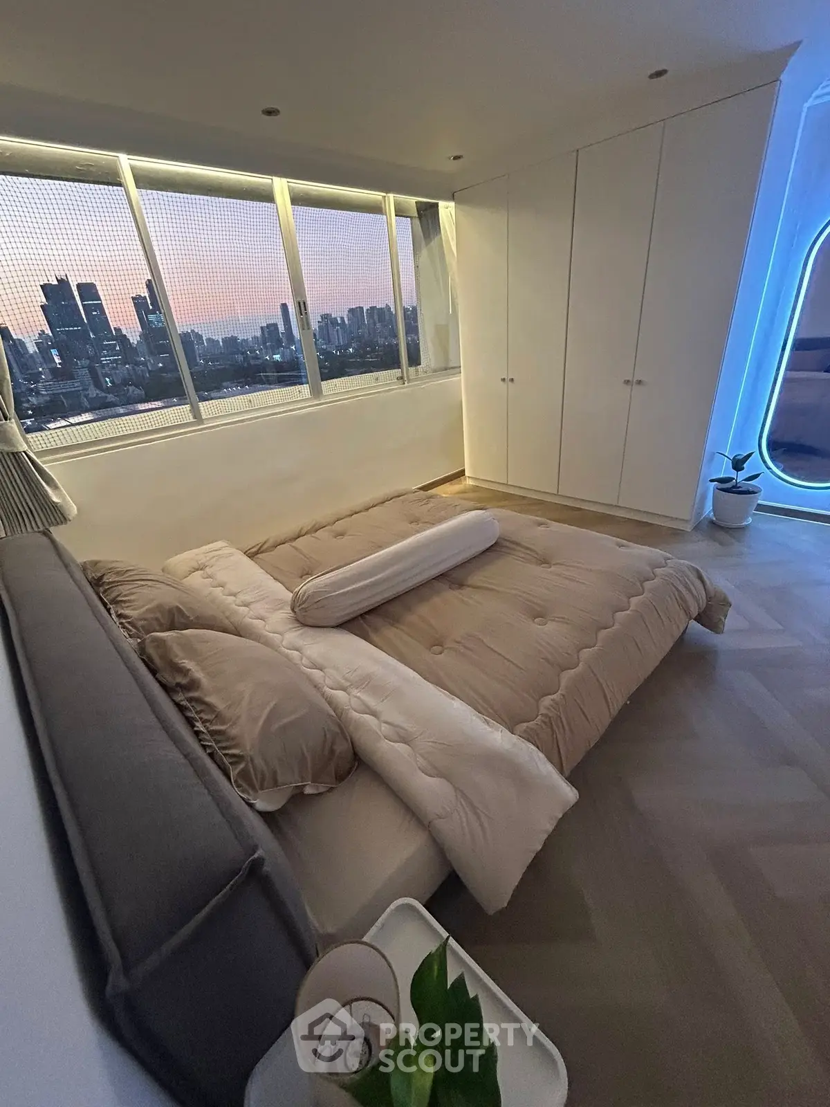 Modern bedroom with city view, featuring sleek design and large windows for natural light.