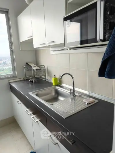 Modern kitchen with sleek countertop and built-in microwave, offering a city view.