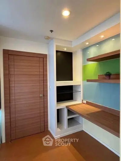 Modern study room with built-in wooden shelves and desk, featuring colorful wall panels and recessed lighting.