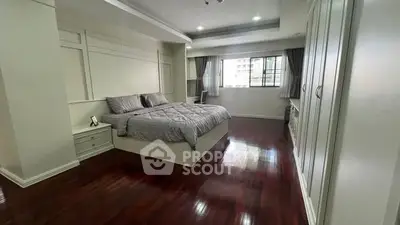 Spacious bedroom with elegant hardwood floors and large window offering natural light.