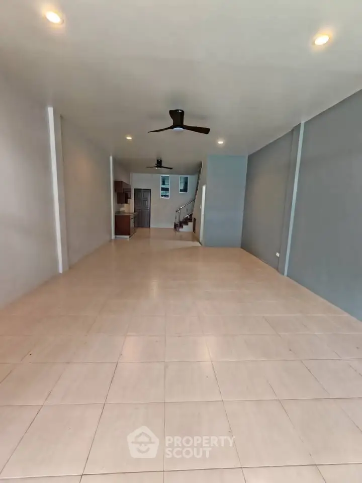 Spacious open-plan living area with ceiling fan and tiled flooring, ideal for modern living.