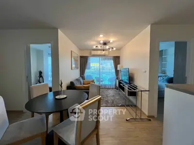 Spacious modern living room with elegant dining area and large windows offering natural light.