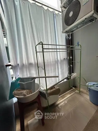 Compact laundry area with drying rack and air conditioning unit, ideal for urban living.