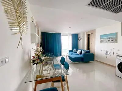 Modern living room with blue accents and glass dining table in a stylish apartment.