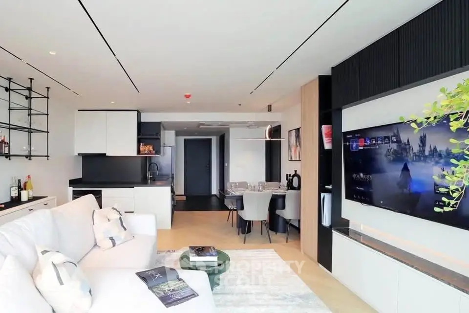 Modern open-plan living room with sleek kitchen and large TV, perfect for entertaining.