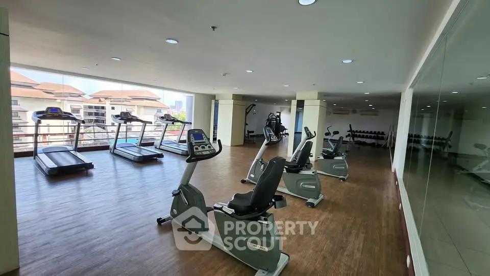 Spacious gym with modern equipment and large windows offering a scenic view.