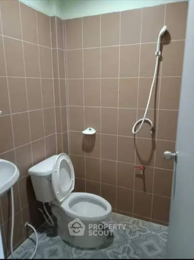 Simple bathroom with brown tiles and showerhead, ideal for compact spaces.