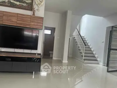 Spacious modern living room with sleek staircase and large TV unit, perfect for family gatherings.