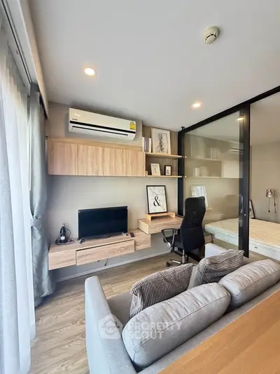 Modern living room with stylish decor and integrated workspace, featuring a cozy sofa and sleek shelving.