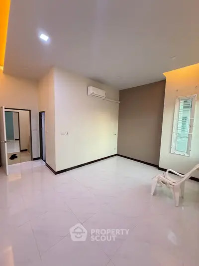 Spacious modern living room with sleek tile flooring and minimalist design, featuring air conditioning and ample natural light.