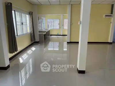 Spacious open-plan living area with large windows and glossy tiled floors, perfect for modern living.