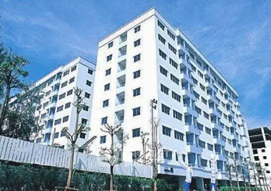 Modern white apartment building with blue sky backdrop, showcasing urban living.